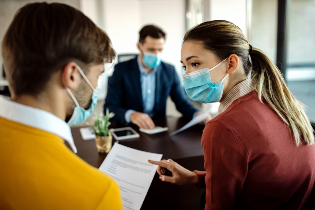 young couple with face masks discussing about paperwork during a young couple with face masks discussing about paperwork during a